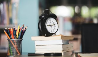 Book,laptop,pencil,clock on wooden table in library,education le