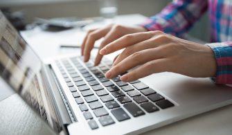 Cropped View of Hands Typing on Laptop