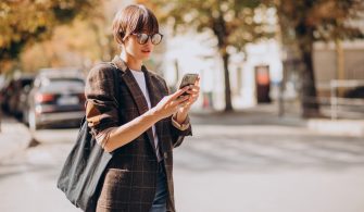 Young woman crossing road and using phone