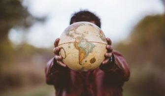 closeup-shot-male-wearing-leather-jacket-holding-globe-front-him_181624-5047