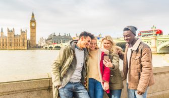 Happy multiracial friends group using smartphone in London