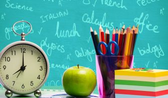 Apple and alarm clock on pile of books