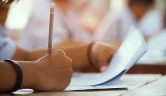 Closeup to hand of student  holding pencil and taking exam in cl