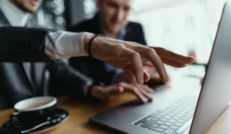 Two businessmen pointing laptop screen while discussing