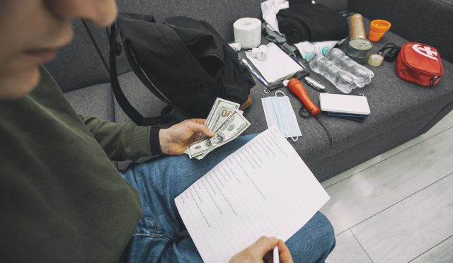 Young man packing the bag with documents, water,food, first aid