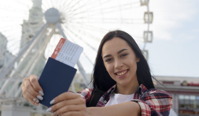 portrait-smiling-woman-showing-air-ticket-passport